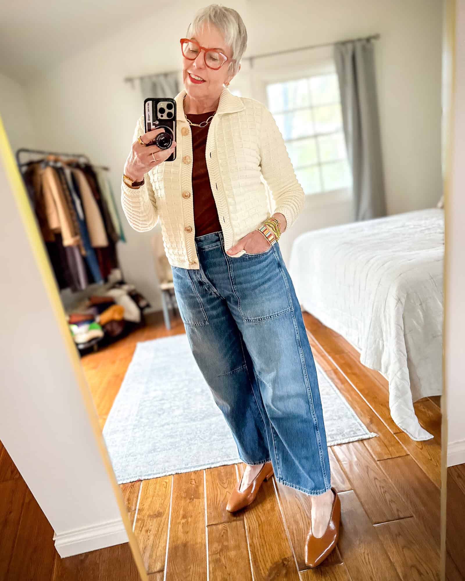 Susan B. wears an ivory cotton polo cardigan with dark brown tee, colorful beaded bracelets, barrel leg jeans, brown pointed toe flats.