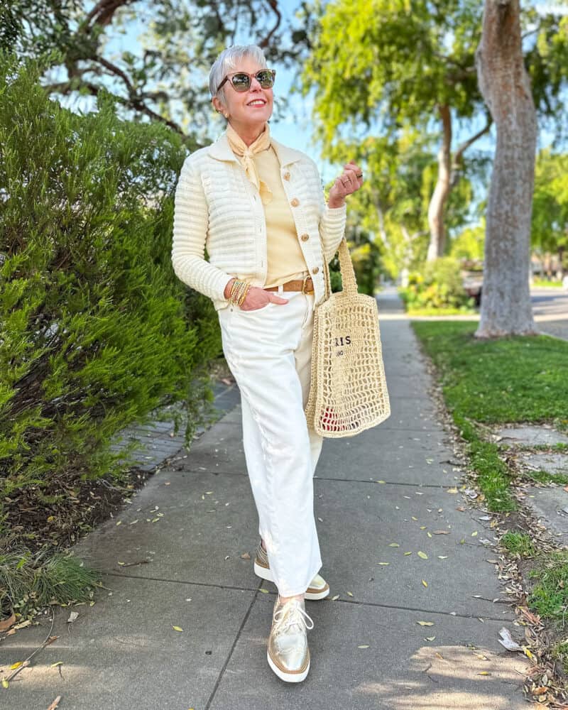 White jeans with yellow: Susan B. wears a textured cotton cardigan, yellow bandana, yellow tee, white jeans, gold oxford shoes, carries a woven straw tote bag.