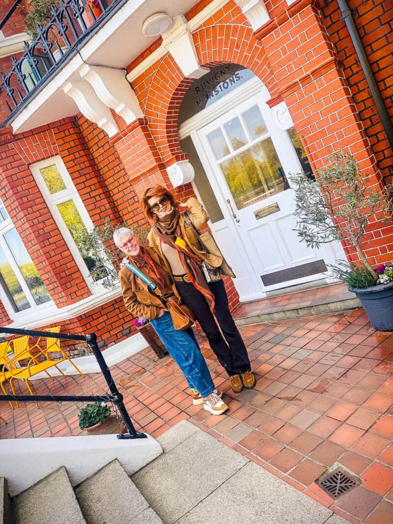 Susan B. arrives in London, met by Annie C. in front of brick building.