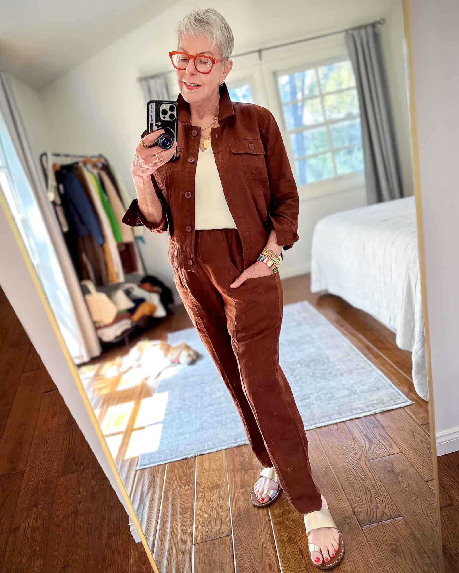 Susan B. wears a matching brown linen jacket and pants from Quince with gold flat sandals.
