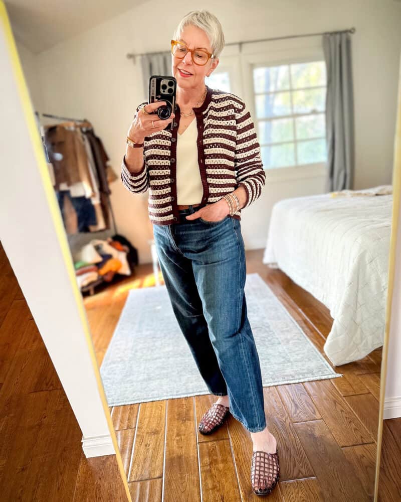 Susan B. wears a Madewell open stitch brown and cream striped cardigan with barrel leg jeans and Vince jelly mules.