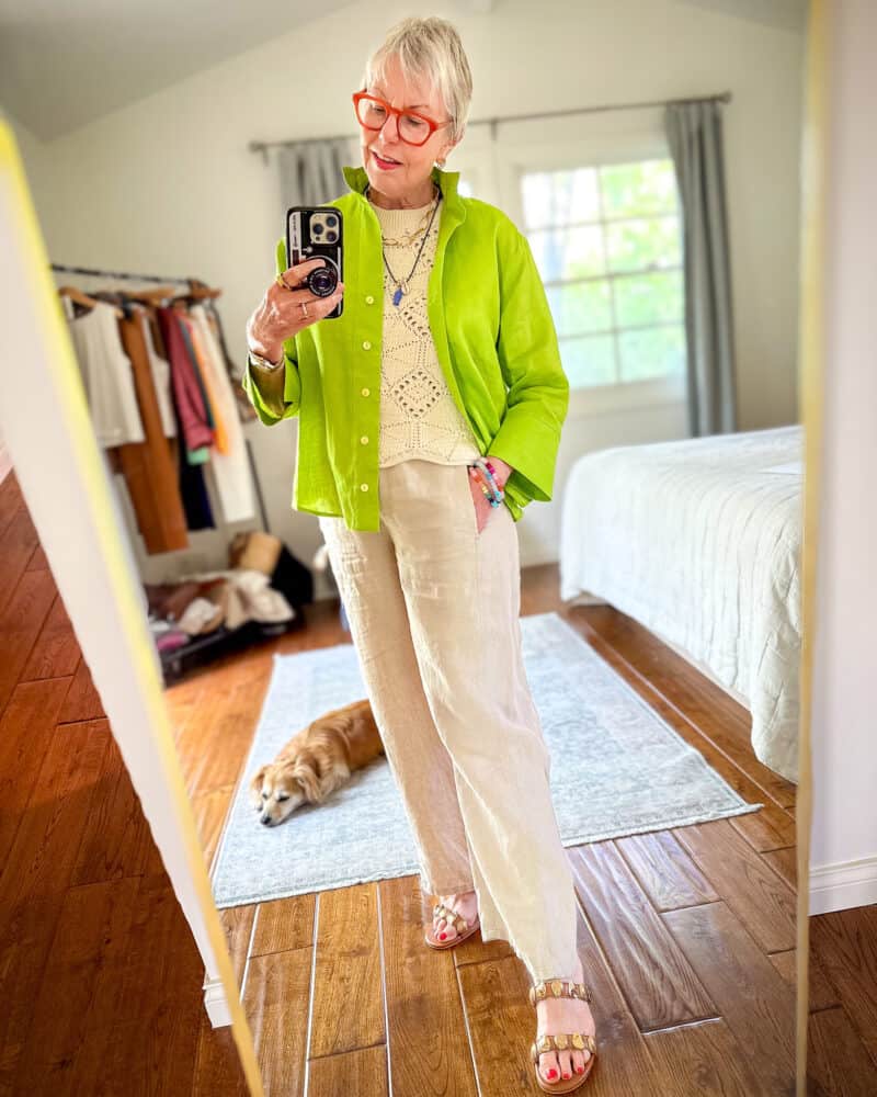 Susan B. wear a bright green linen shirt over a crochet tank and beige linen trousers with embellished sandals.