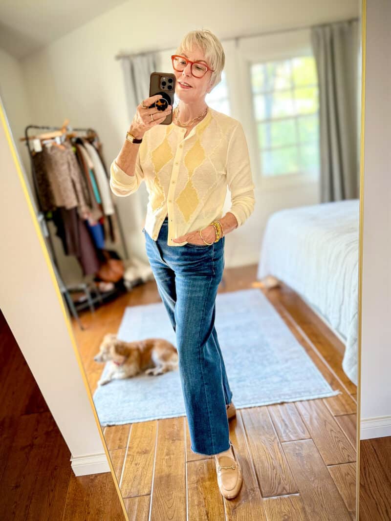 Susan B. wears a cream and butter yellow argyle cardigan with straight leg jeans and tan horsebit loafers.