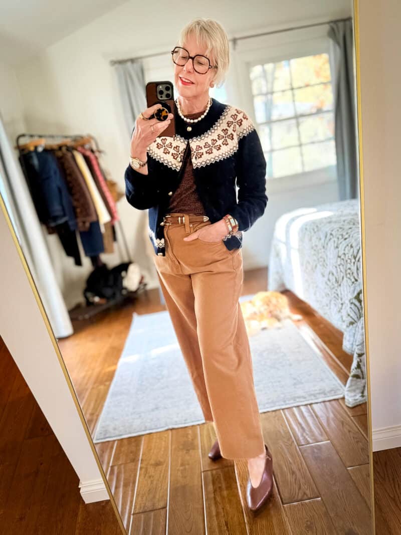 Susan B. wears a navy Fair Isle cardigan, brown tee, tan belt, tan jeans, and brown pointed-toe flats.