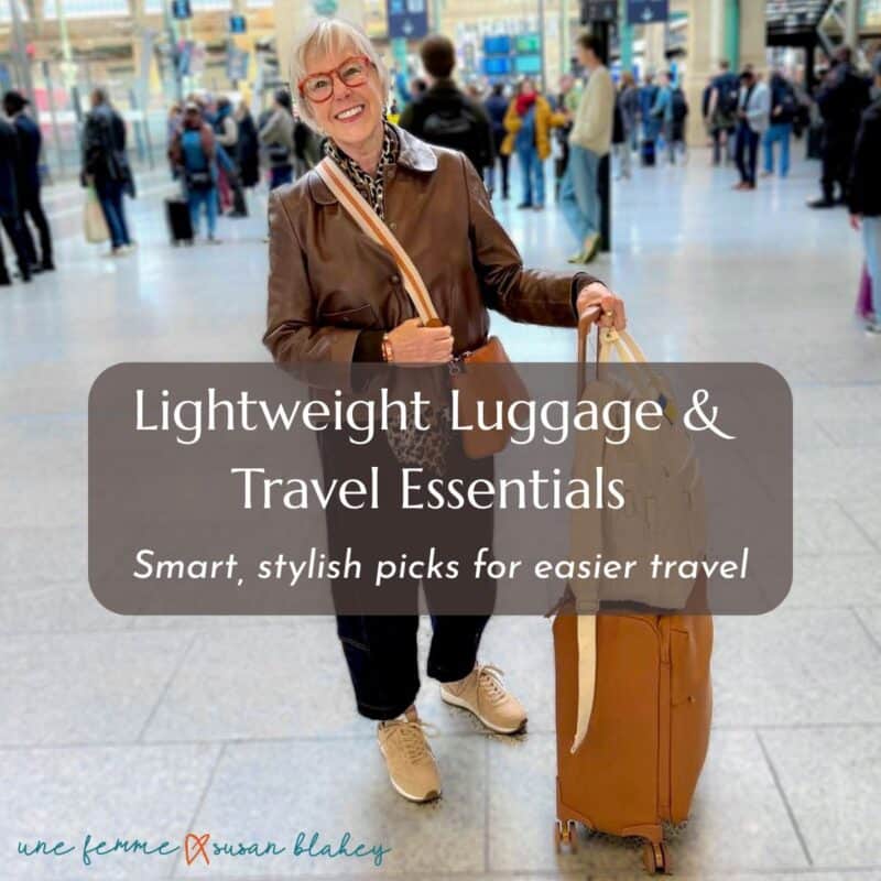 Susan B. arrives in Paris wearing a brown leather jacket, barrel-leg jeans and sneakers. Luggage is spinner bag by Lipaul and Beis backpack.