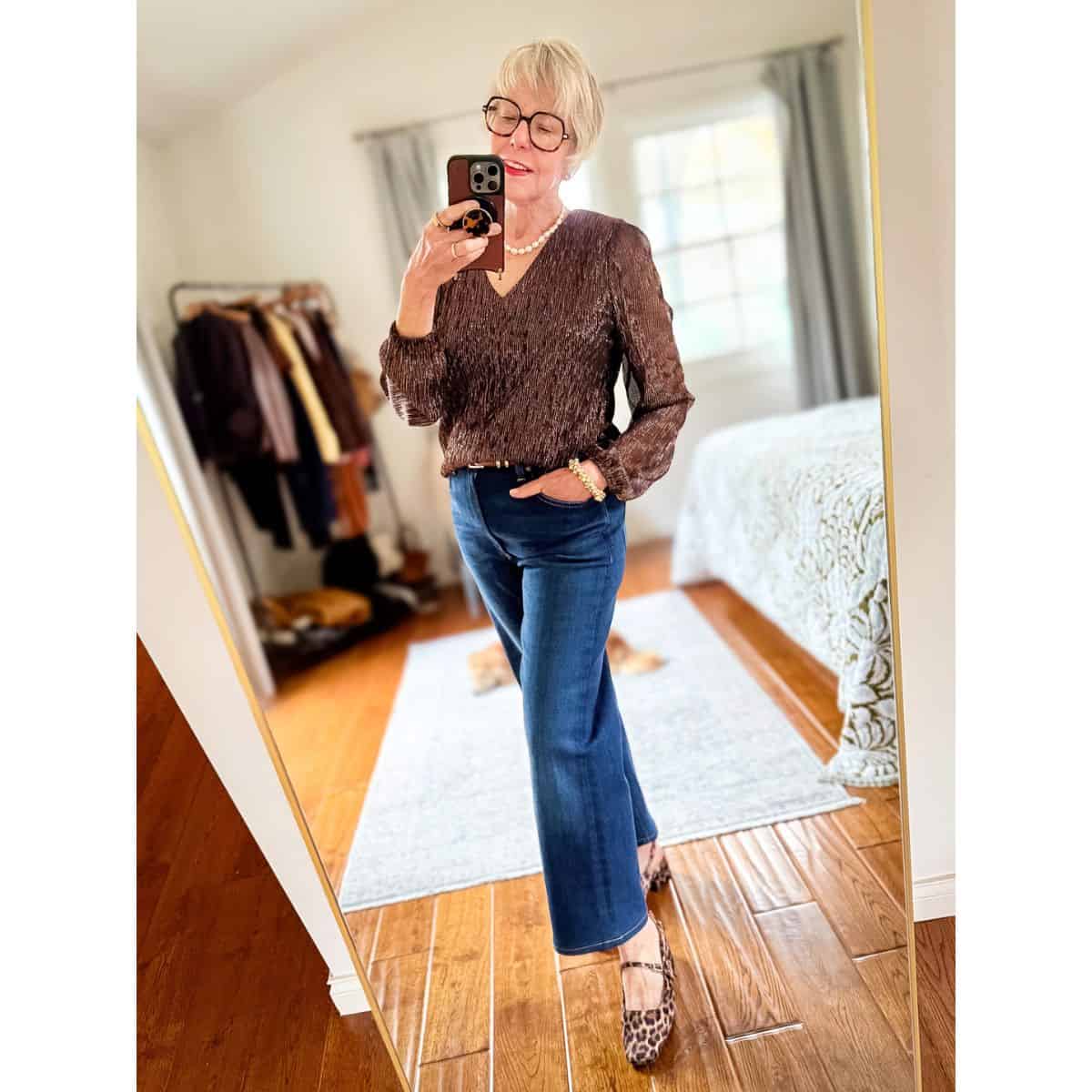 Susan B. wears a pearl necklace, bronze shimmer v-neck top, straight leg jeans, leopard print slingback shoes.