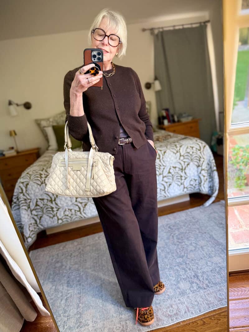 Susan B. wears a dark brown cashmere cardigan and wide leg trousers, leopard print adidas sneakers, carries an MZ Wallace small Park Satchel in Buff.