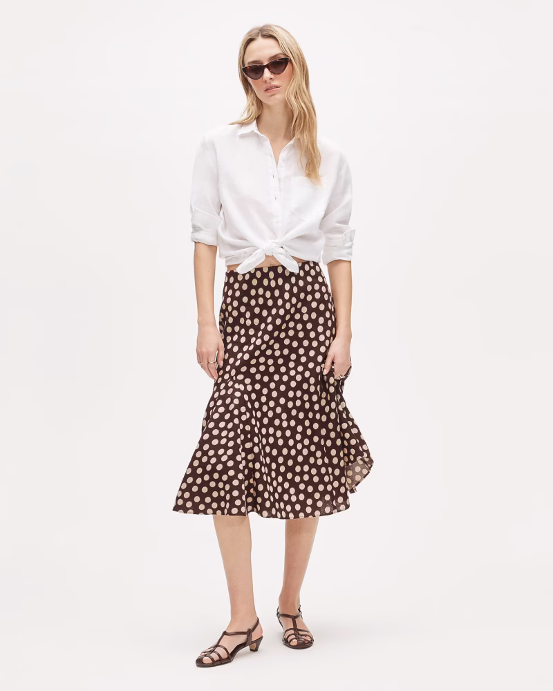 J.Crew brown polka dot skirt with flounce hem in linen, styled with a white shirt tied at the waist.