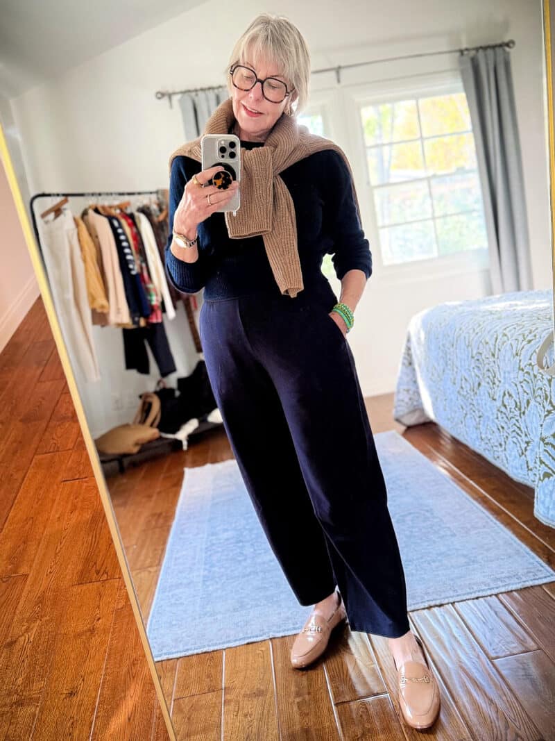 Susan B. wears Eileen Fisher stretch crepe "Arch" pants in Ink (navy), with a navy cashmere sweater and tan fisherman sweater tied over the shoulders.