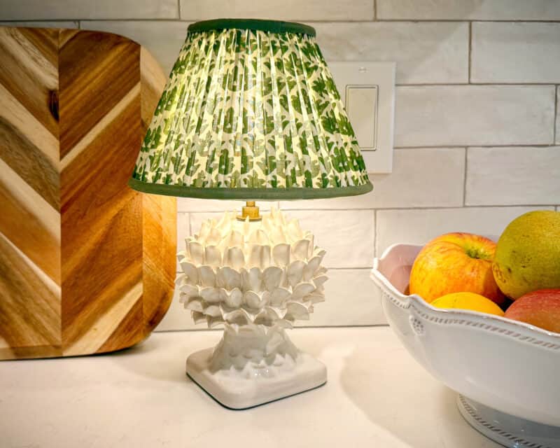 Cordless light from Pooky on kitchen counter with wooden cutting board and bowl of fruit.