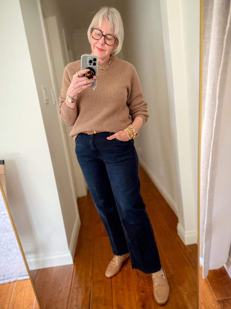 Susan B. wears a light brown cashmere fisherman sweater with dark wash straight leg jeans and tan loafers.