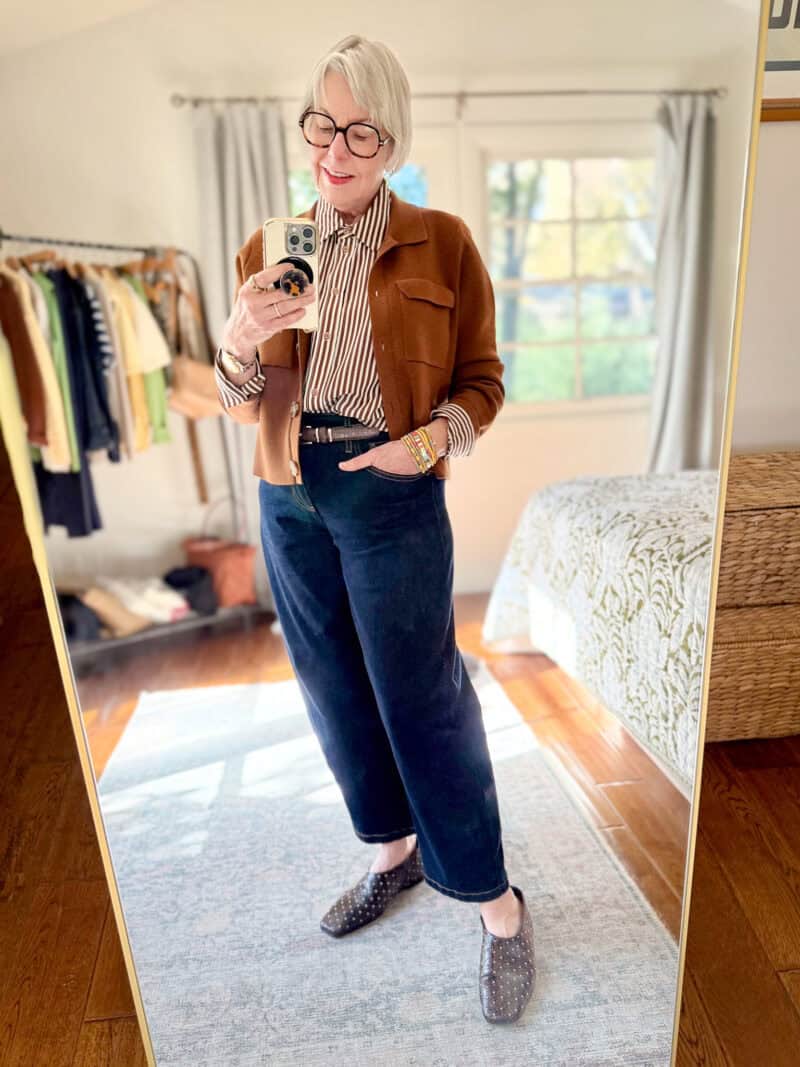 Polished casual outfit with a striped silk shirt, brown sweater jacket, barrel-leg jeans, studded flats.