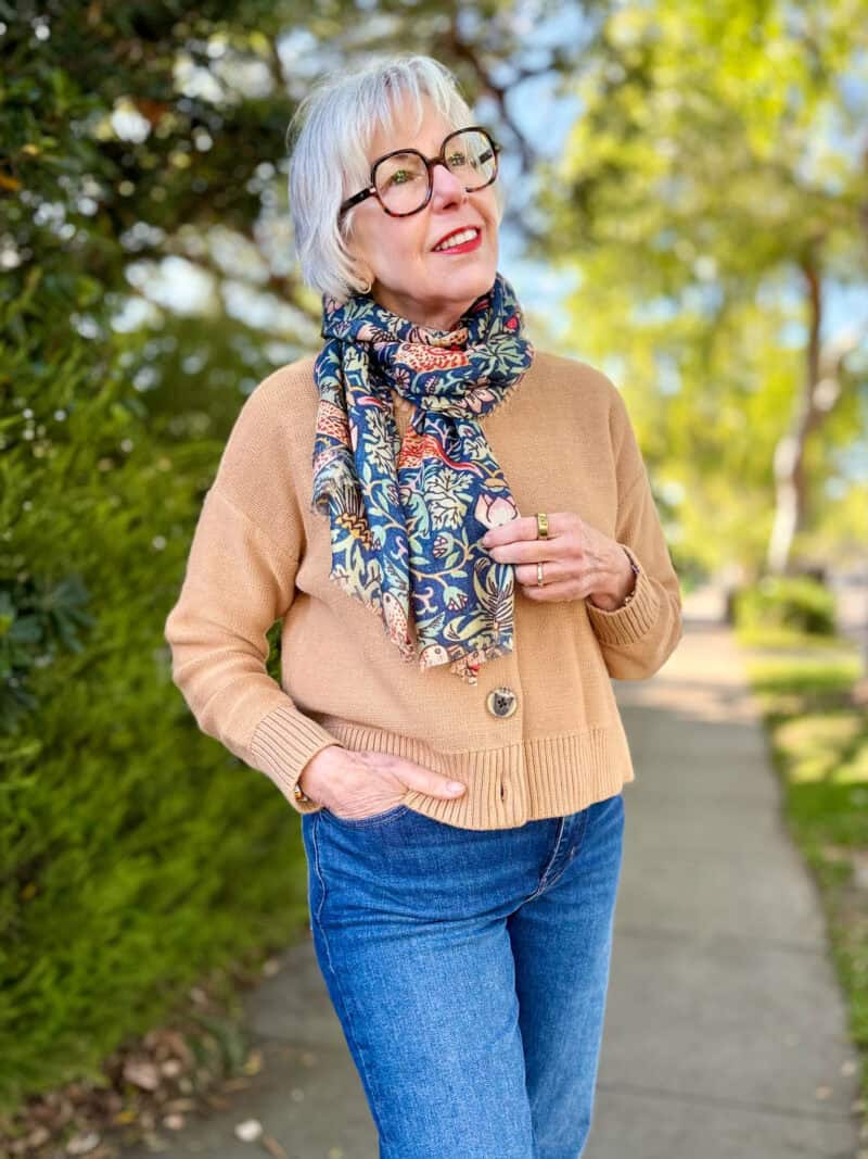 Susan B. wears a Liberty print scarf over a camel cotton cardigan and jeans.