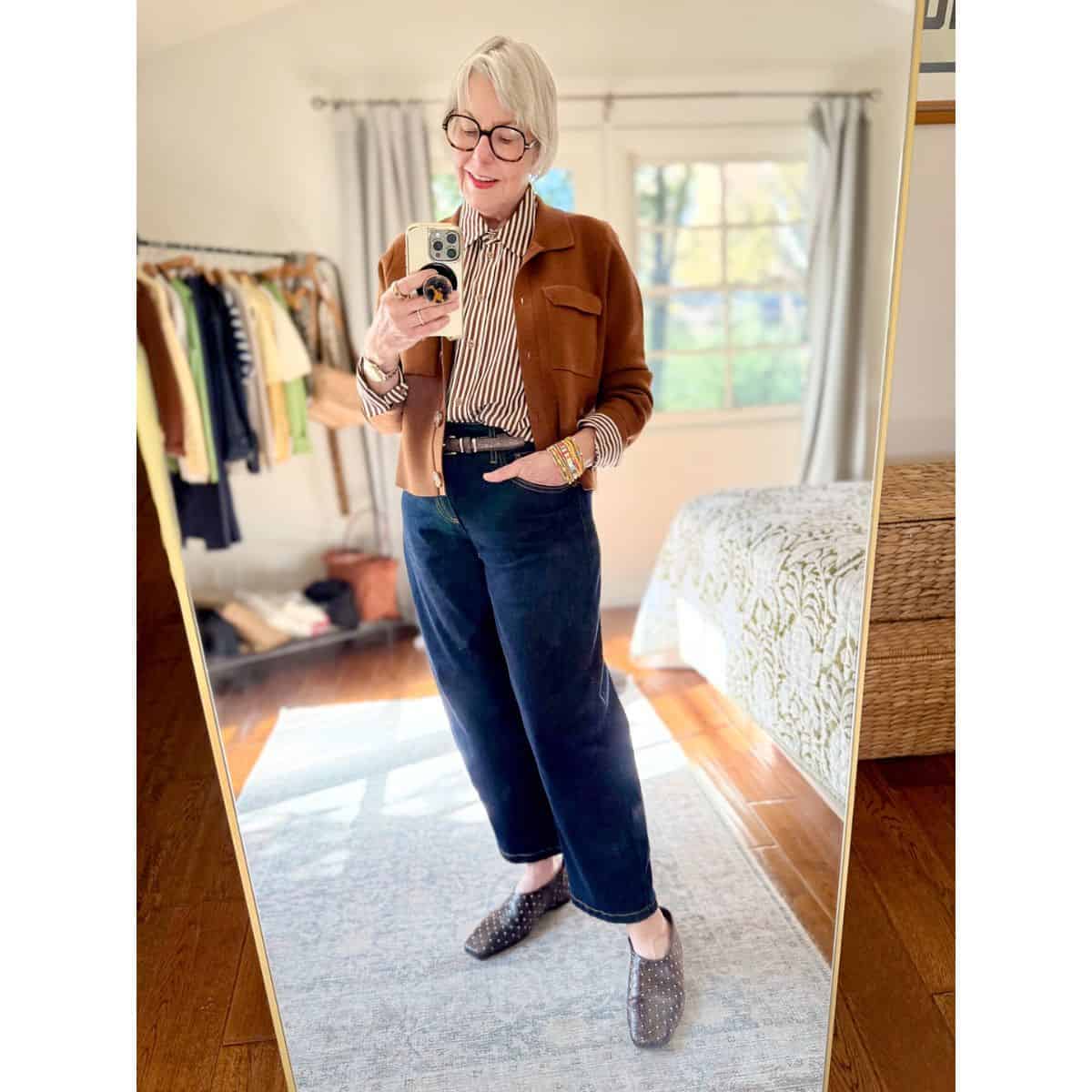 Polished casual outfit with a striped silk shirt, brown sweater jacket, barrel-leg jeans, studded flats.