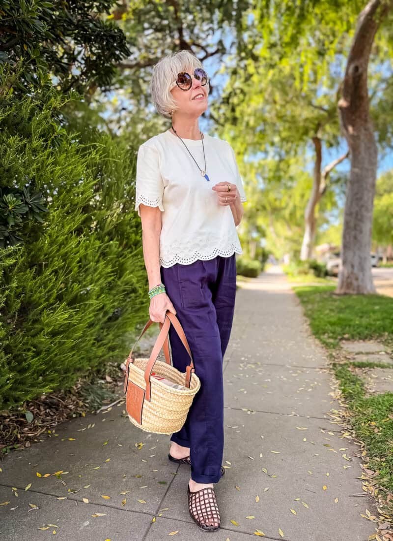 spring outfit idea with a scallop hem tee, navy linen pants, jelly sandals and raffia basket bag.