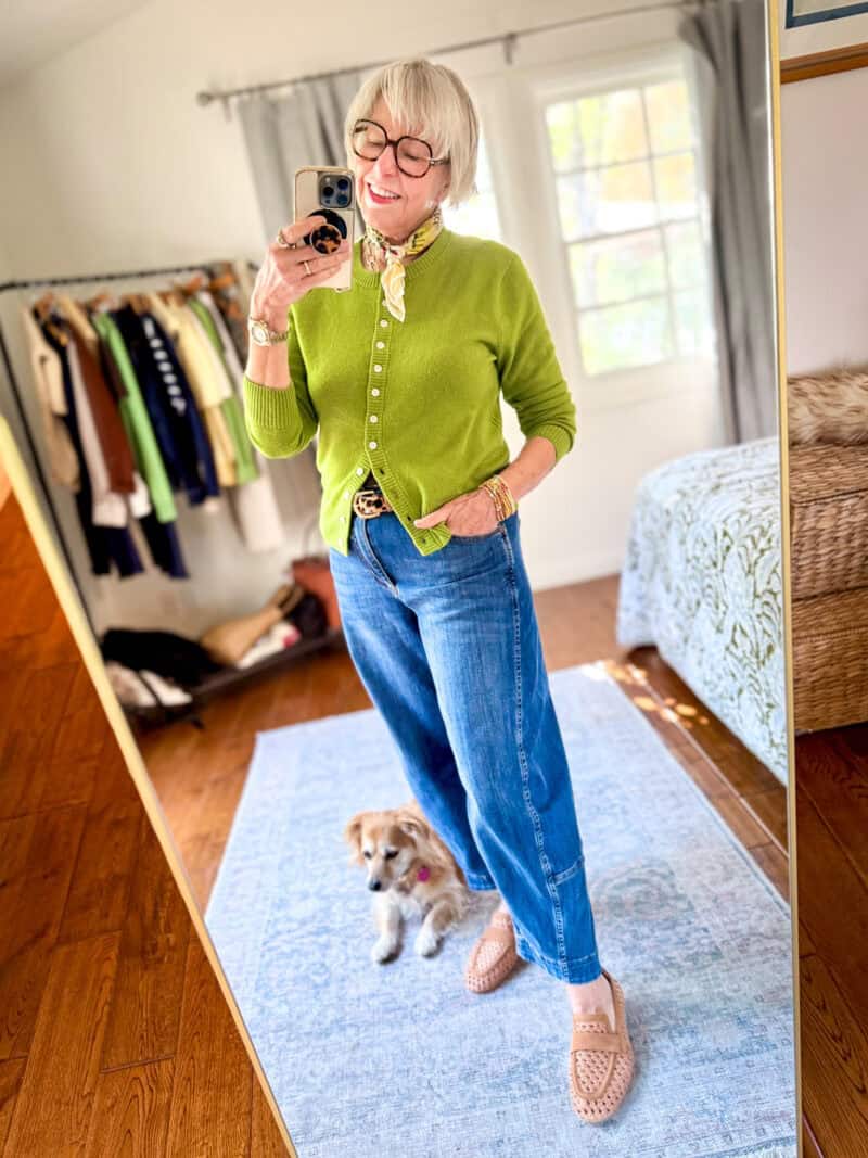 Susan B. wears a peridot green cashmere cardigan, leopard print belt, barrel-leg jeans, woven leather loafers.