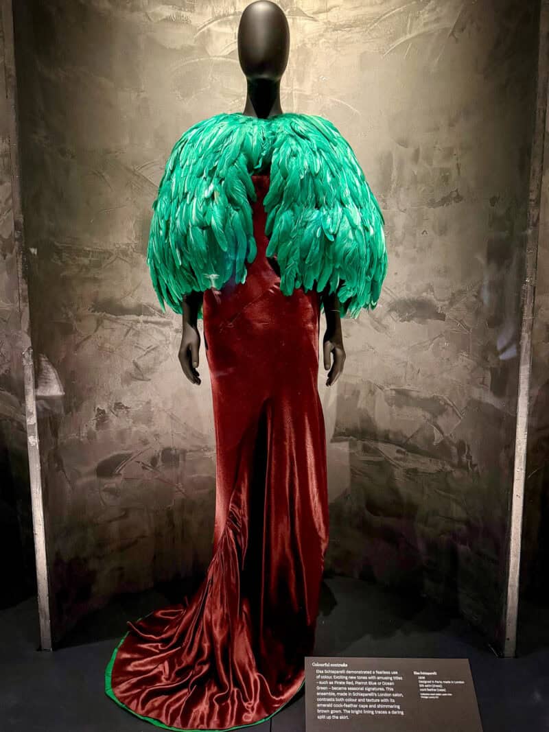 Brown velvet gown with green feathered cape at the Schiaparelli exhibition V&A London.
