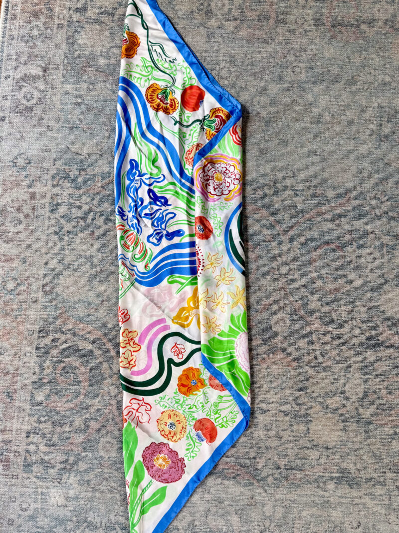 Printed silk scarf folded on the diagonal, pointed end folded in to start bias fold.