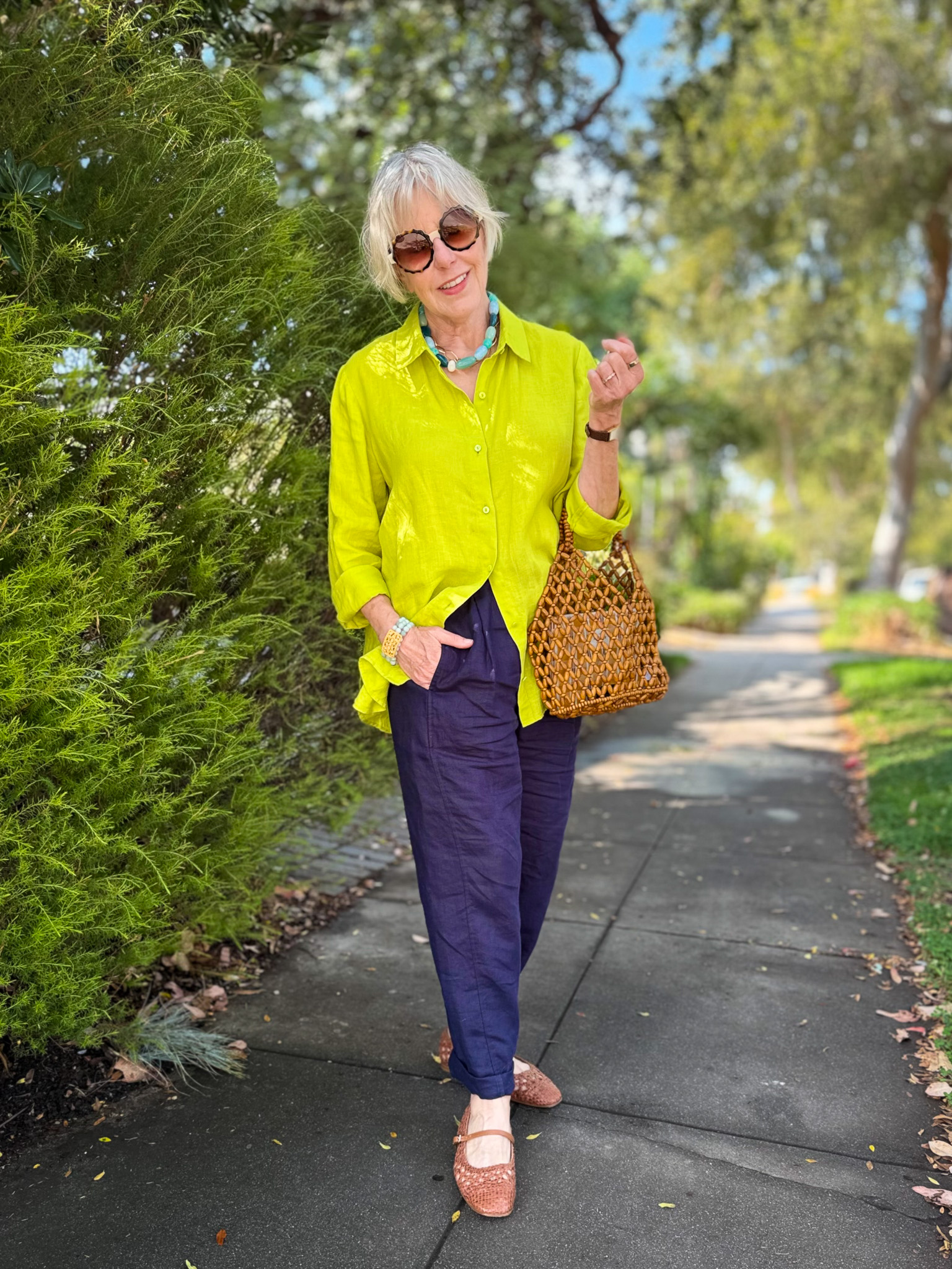 Full-length outfit with Eileen Fisher chartreuse linen shirt, navy linen pants, woven leather Mary Jane flats, and a wooden bead bag