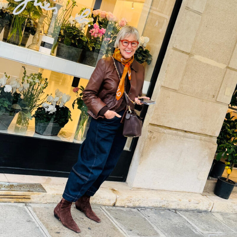 Susan B. wears dark wash barrel jeans and a brown leather jacket in Paris.