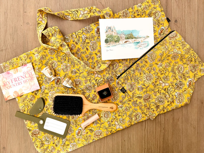 French gifts from My French Country Home: printed tote and matching pouch, Paris print, gold and stone ring, antique silver egg cups, luggage tag and tech case, boar bristle brush, and tinted lip balm.