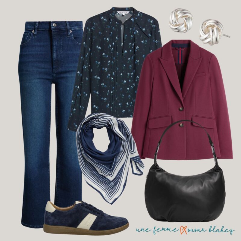 Travel outfit idea with straight leg jeans, navy floral top, burgundy blazer, silver earrings, navy striped scarf, navy sneakers, black leather bag.
