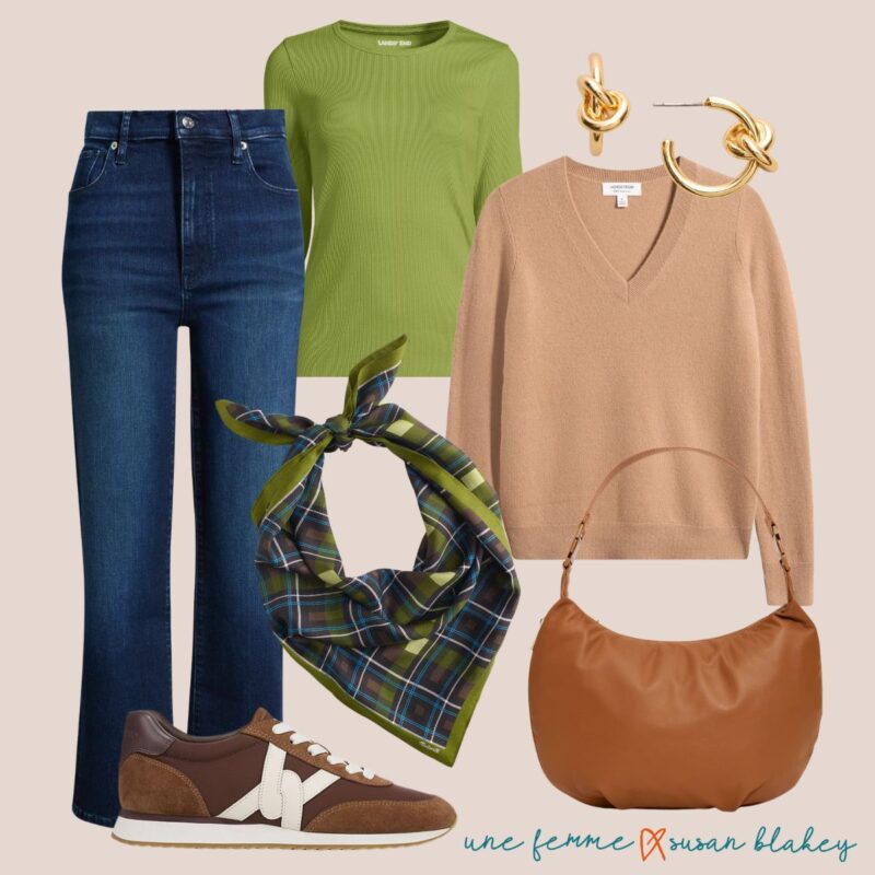 Fall travel outfit idea with warm neutrals: straight-leg jeans, green tee, camel v-neck sweater, gold knot earrings, blue and olive plaid bandana, brown sneakers, brown leather bag.