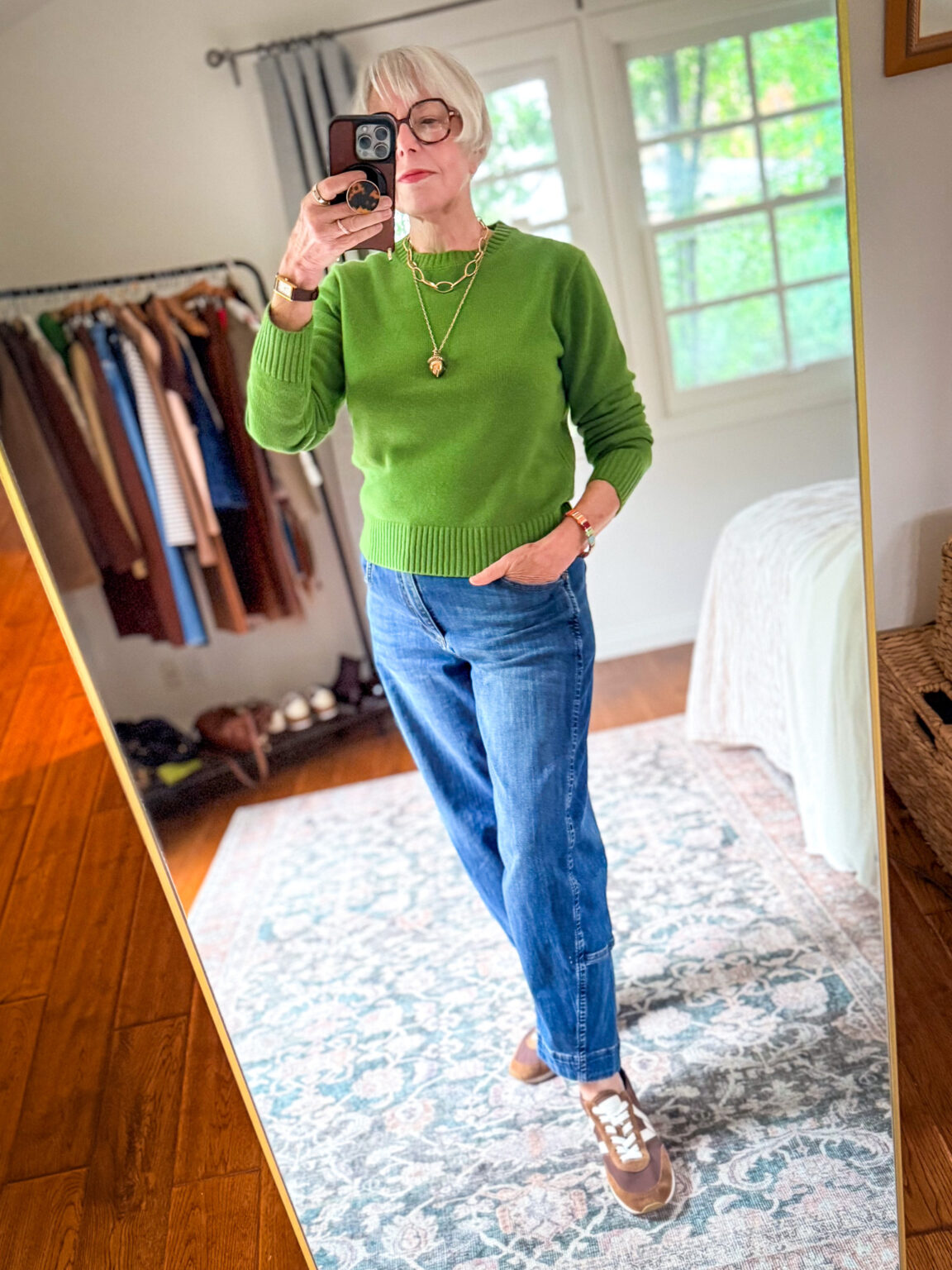 Woman wearing a bright green Madewell merino sweater with barrel-leg jeans, brown sneakers, and layered gold necklaces.