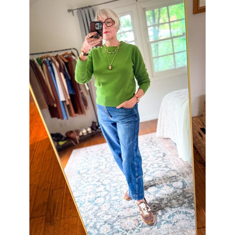 Woman wearing a bright green Madewell merino sweater with barrel-leg jeans, brown sneakers, and layered gold necklaces.